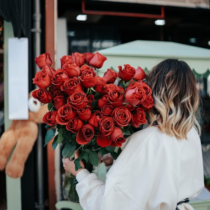 A person holding a large bouquet of red roses.